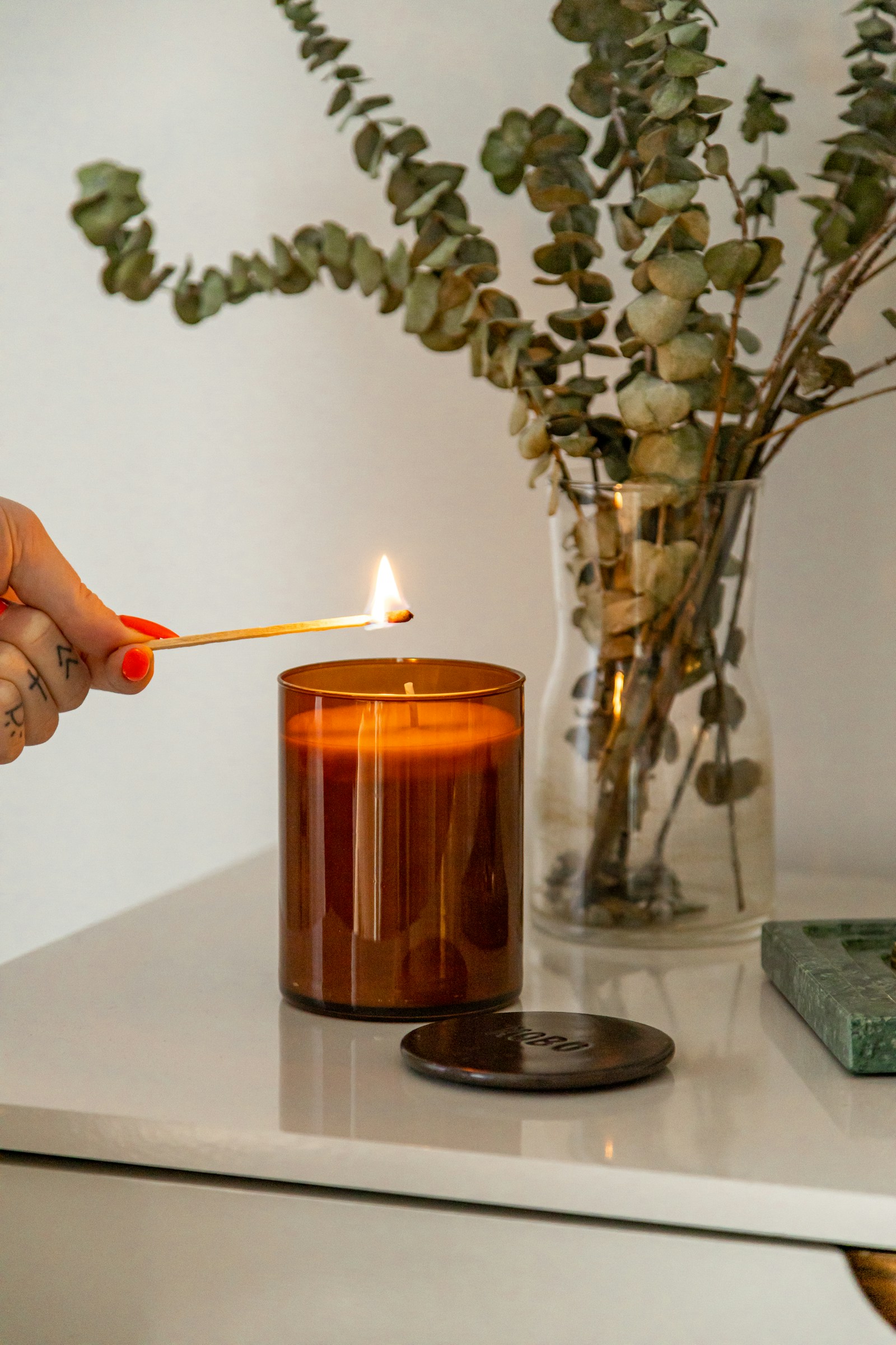 A hand lighting an amber candle