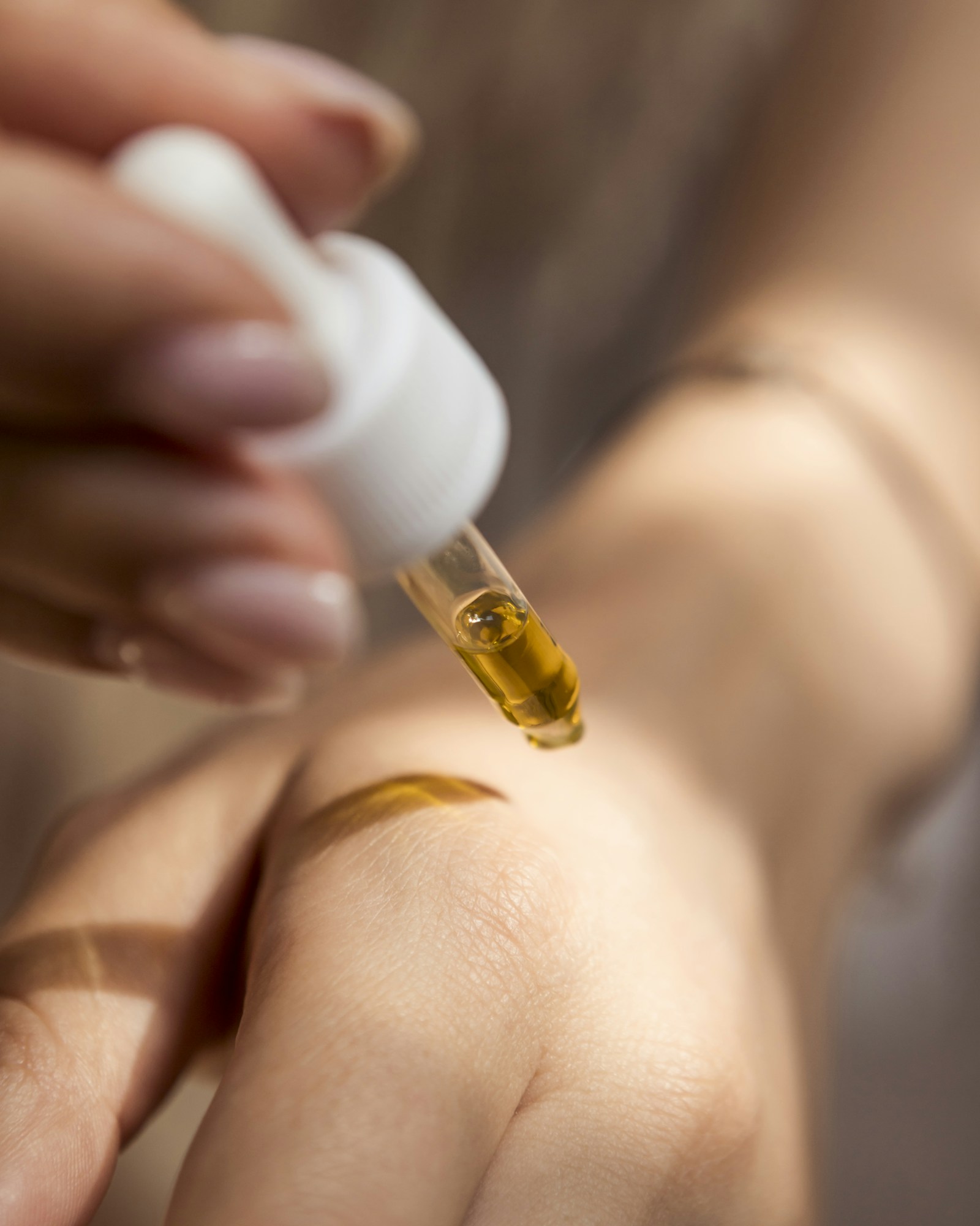 A skincare dropper held above skin